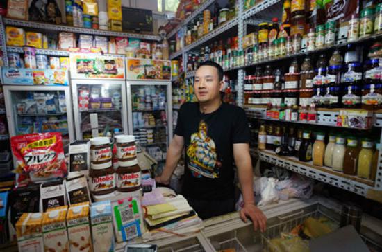 5月8日，在三源里市場081號商鋪，店主張海標(biāo)在介紹自己的商店。